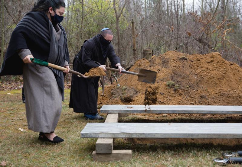 Masked priests dig grave with shovels 