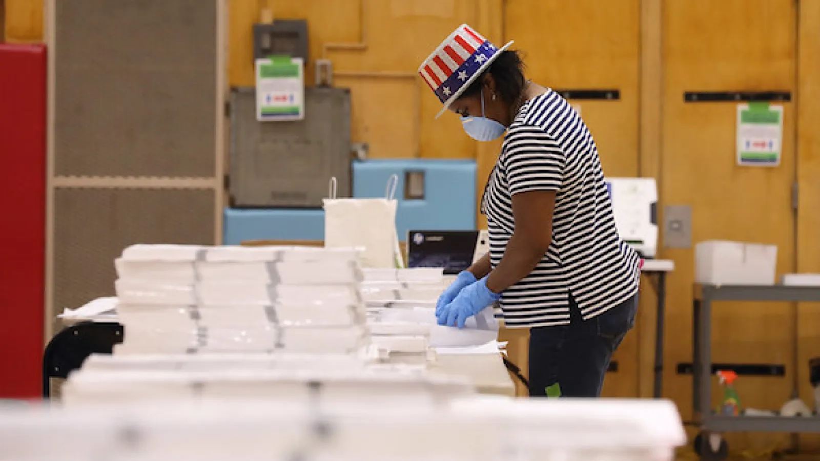 Poll worker sorts ballots while wearing mask