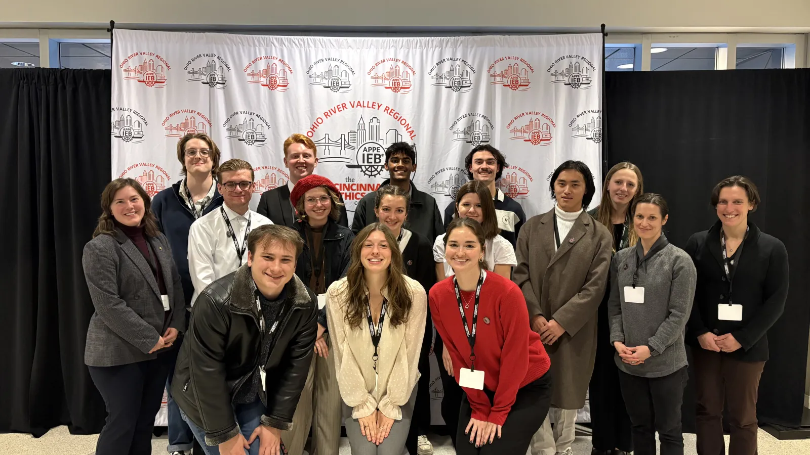 The OSU Ethics Bowl Team (12 students and three coaches) pose together in front of a screen that says Ohio River Valley Regional Competition
