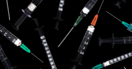 multiple syringes scattered on a black background