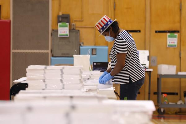 Poll worker sorts ballots while wearing mask