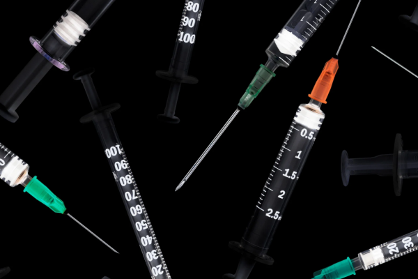 multiple syringes scattered on a black background