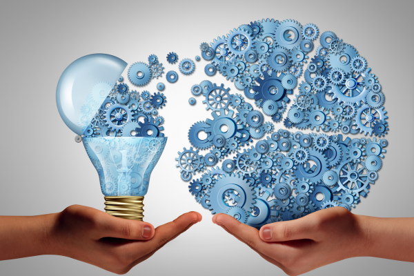 Two hands with palms facing up. One hand holds illustration of lightbulb with gears coming out of it. These gears are connected to many more gears being held in the other hand.